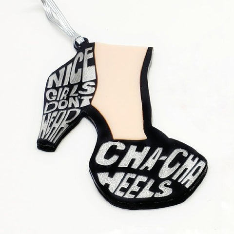 Laser cut acrylic ornament in the shape of a foot wearing a black heeled shoe with the caption “Nice girls don’t wear cha cha heels” written in metallic silver
