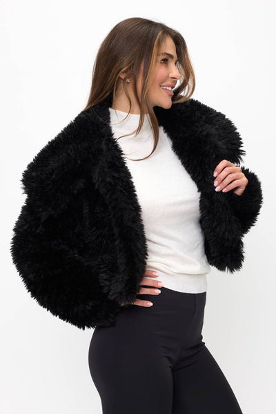 model wearing a black faux fur fluffy cropped jacket with oversized round collar. Shown from front