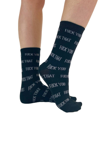 black crew socks with knit-in pattern of phrases "FUCK YOU" "FUCK THAT" "FUCK ME" "FUCK OFF". Shown from the side worn by a model