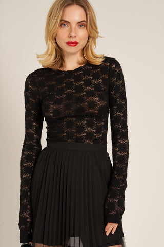 Model wearing a black lace top with floral pattern. Shown from front