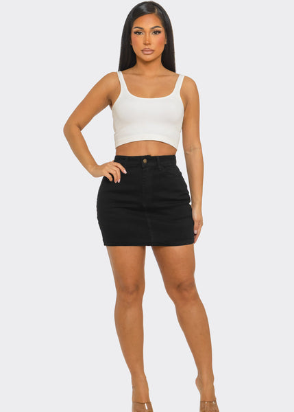 model wearing black denim high-waisted mini skirt with 5 pockets and a zip & button front closure. Shown from front