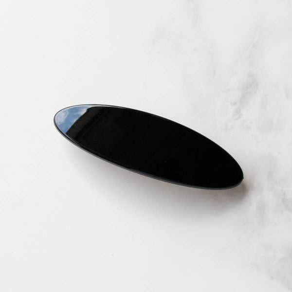 black acrylic oval shaped barrette. Shown from front