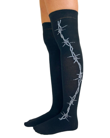 over-the-knee length socks in solid black cotton with white knit in pattern of barbed wire running down the outer leg of each sock, shown on model