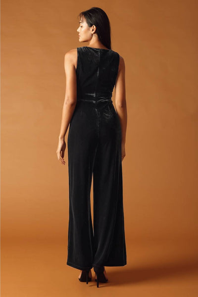 model wearing black velvet jumpsuit with boatneck and seamed sleeveless bodice, banded waistband, and wide legs. Shown from back
