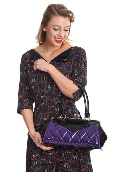 Vintage-inspired handbag made of black and red vinyl with purple pearly quilted body and black sides & top with matching black handles. Purse has silver metal kiss lock opening and matching detachable shoulder strap. Shown worn by model