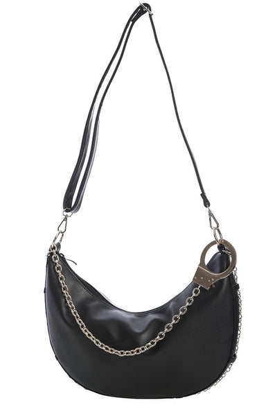 Black faux leather crescent shaped slouchy shoulder bag with matching faux leather shoulder strap and matching silver chain running across the bottom of the bag. Shown from front with handcuff strap used as bag charm 