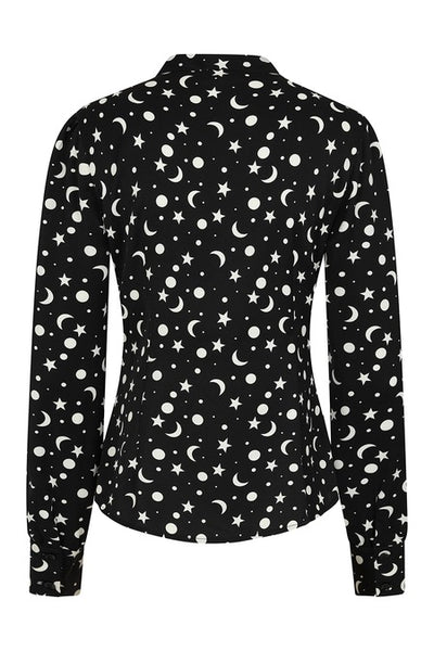 a matte finish satin long sleeve button down blouse in a black background scattered white star, crescent moon, and full moon allover pattern with a tie neck collar, slightly puffed shoulders, and button cuffed sleeves. Shown from back