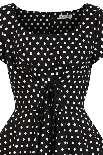 cotton fit and flare style short sleeve dress in a crisp black and white polka dot pattern, featuring a scoop neckline and fitted bodice with underbust lacing, and a full knee length skirt. showing a cropped close up of the bodice