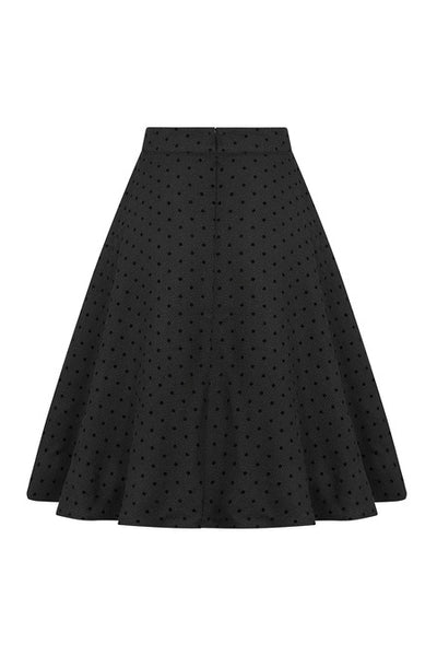 black high-waisted circle swing skirt with side seam pockets in textured woven fabric with all over pattern of flocked small polka dots. Shown from back
