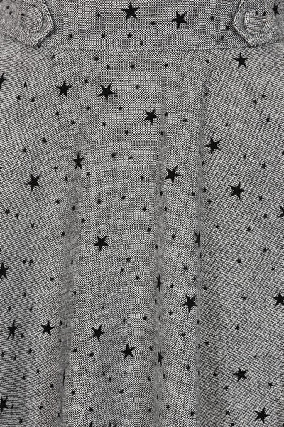 grey tweed high waisted swing skirt with all over flocked black star pattern, fabric covered button detail at waistband, and pockets. Shown from front in close up of fabric texture and pattern