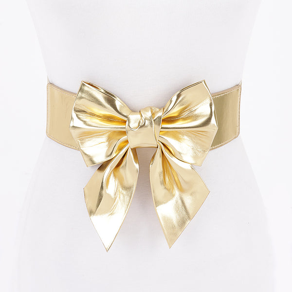 Metallic gold faux leather waist belt with large asymmetrical bow shown from front on dress form