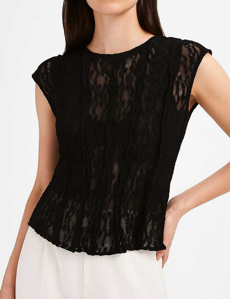 model wearing a black floral patterned lace top with round neckline, short cap sleeves, and vertical ruffle details. Shown from front in close up