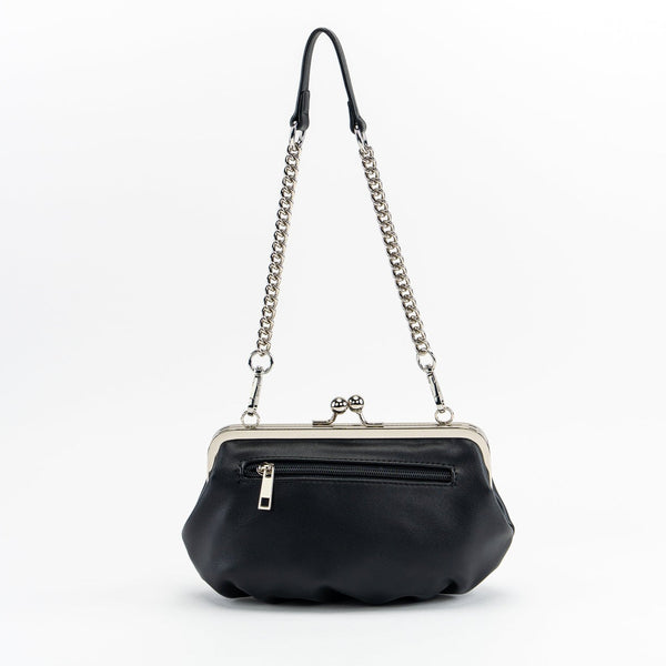black textured faux leather purse with silver metal kiss lock and silver metal stars, crescent moons, and sun embellishments. Attached is an 11" chain link and faux leather shoulder strap. Shown from back to display plain side of purse with exterior zipper pocket