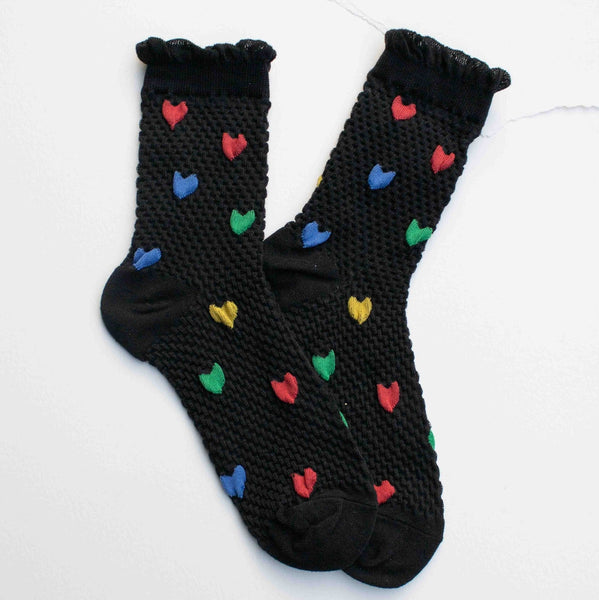 black cotton socks with waffle texture knit, ruffled cuffs, and knit-in pattern of red, blue, green, and yellow hearts