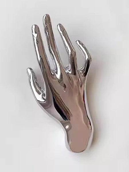 Silver metal brooch of an outstretched hand. Shown flat