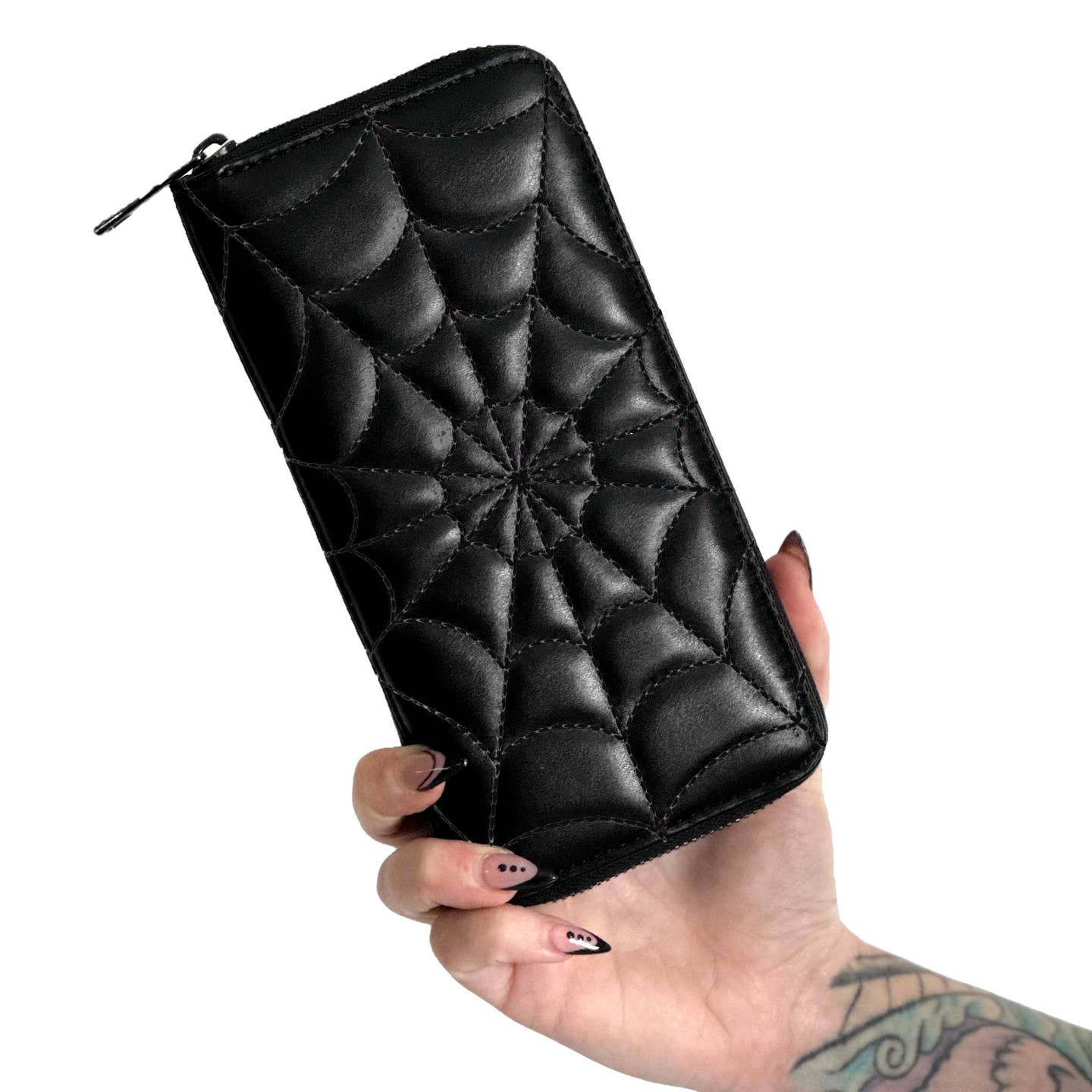 black faux leather with spiderweb-stitched front wallet and three sided zipper. Shown closed held by model