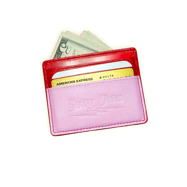 rectangular faux leather 6 slot card holder in bright red and bubblegum pink with diagonal hot pink faux leather lightning bolt applique in middle. Shown from back with cards and cash