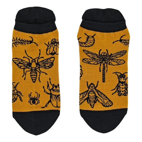 mustard unisex ankle socks with black toes,heels, and cuffs with an all over pattern of bug illustrations with black outlines including scorpions, dragonflies, centipedes, moths, and spiders. Shown flat