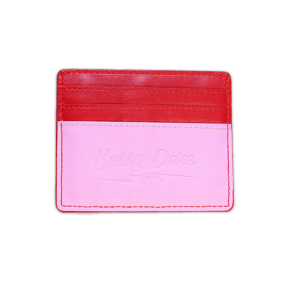 rectangular faux leather 6 slot card holder in bright red and bubblegum pink with diagonal hot pink faux leather lightning bolt applique in middle. Shown from back with solid red and pink side and subtle stamped branding