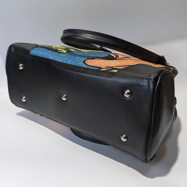 A bowler style purse with a satin body and printed image of comic book Ben Day style  art of a zombie face to face with a screaming woman. The purse has black faux leather handles, protective corners, sides, and bottom. Shown from bottom to display metal feet