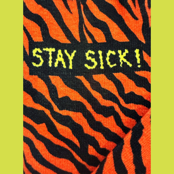 Close up of tiger pattern on ankle of sock with “STAY SICK!” detail on lime green background 
