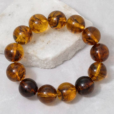 Brown amber translucent marbled round beaded bracelet on a white stone surface