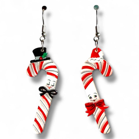 pair of "Candy Cane Couple” smiling anthropomorphic glittery candy canes decorated with bows and a top hat &amp; Santa hat layered laser cut resin dangle earrings