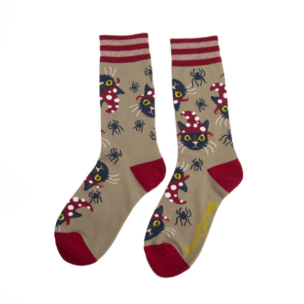 Unisex crew socks in light brown with red striped cuffs and red toes & heels. All over pattern of black cats wearing red and white dotted witch hats and small black spiders. Shown flat from other side