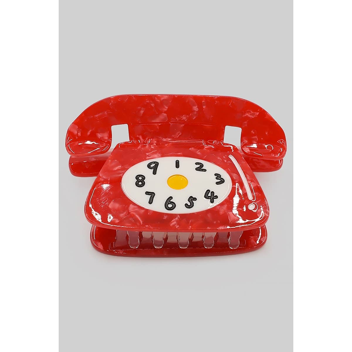 red acetate claw hair clip in the shape of a rotary phone with white, black, and yellow dial