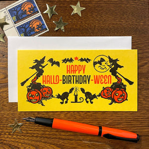 rectangular yellow heavy cardstock letterpress greeting card with "HAPPY HALLO-BIRTHDAY-WEEN" message in black and orange with vintage style illustrations of jack-o'-lanterns, black cats, bats, and witches