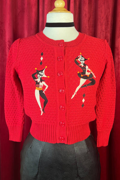 Red cotton pointelle knit sweater with embroidered black and white pair of harlequins design on a mannequin against a red curtain background