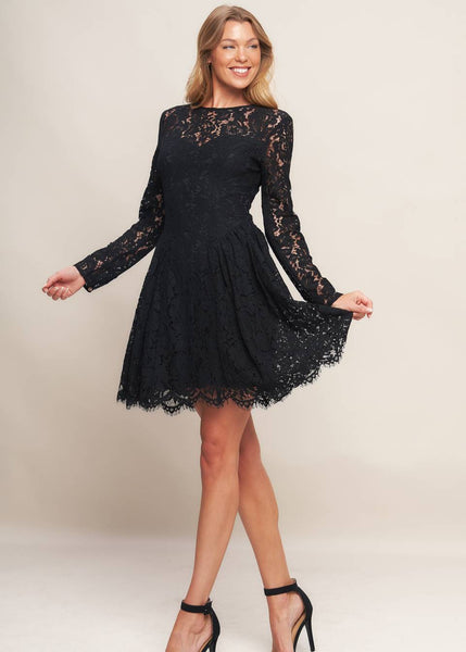 model wearing a black lace mini dress with long sleeves, round neckline with sweetheart style bodice lining, reverse yoke waistband with scalloped hem ending above the knee. Shown from front