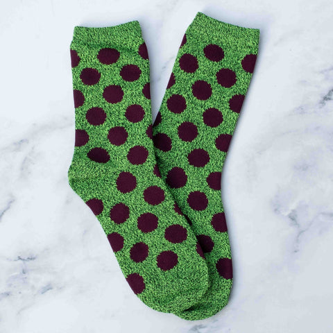bright green heathered socks with dark wine purple polka dots on a marble background