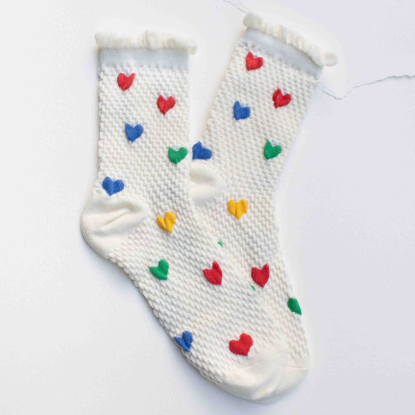 white cotton socks with waffle texture knit, ruffled cuffs, and knit-in pattern of red, blue, green, and yellow hearts