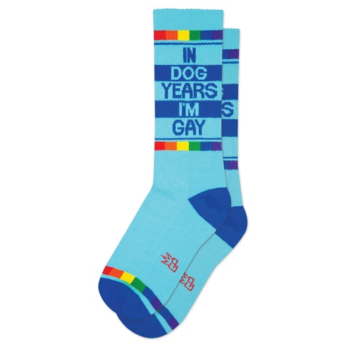 bright blue unisex crew socks with dark blue toes and heels & rainbow cuffs with "IN DOG YEARS I'M GAY" message on side. Shown on white background