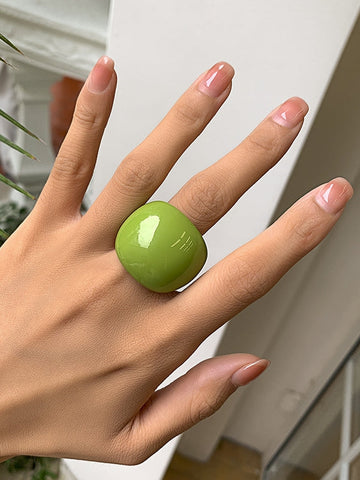 Rounded bright green acrylic cocktail ring. Shown worn by a model