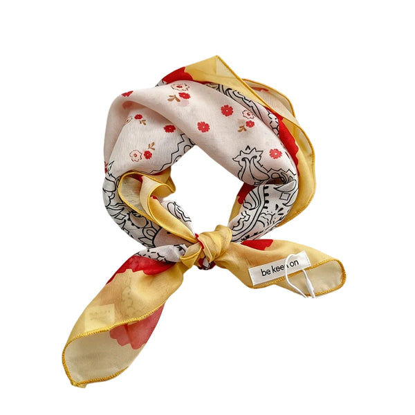 square scarf with white background red and white dainty floral pattern with black outline paisley details and yellow & red scallop border