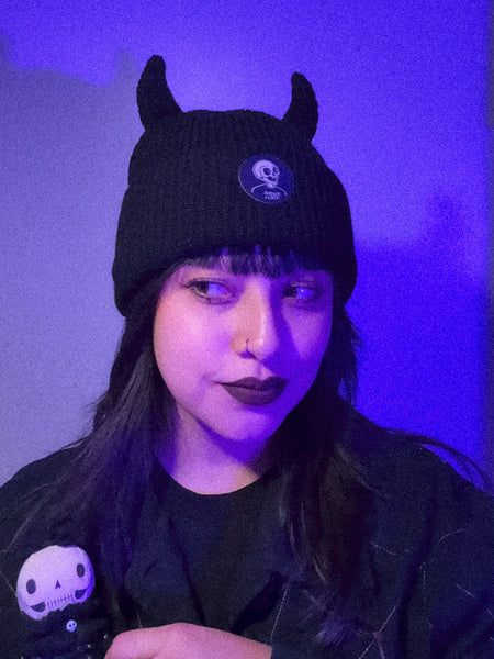 Black ribbed knit beanie with matching black devil horns worn by a model 