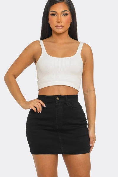 Woman wearing a white crop top and black skirt on a white background