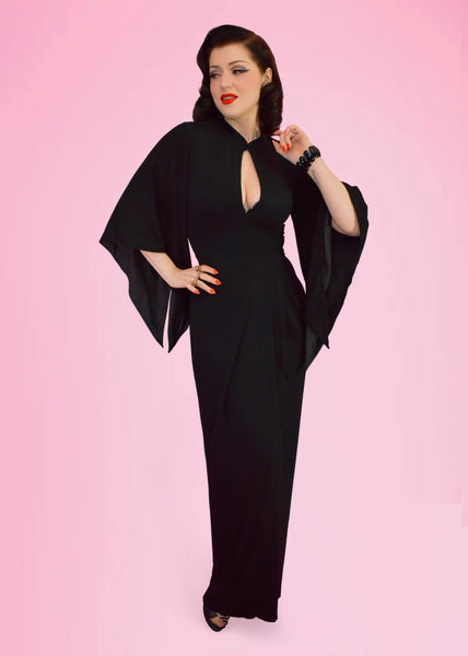 model wearing black brushed fiber knit maxi dress with high rounded collar with keyhole neckline, fitted darted bust, lantern style sleeves lined in black, and sarong-style gathered maxi skirt. Shown from front
