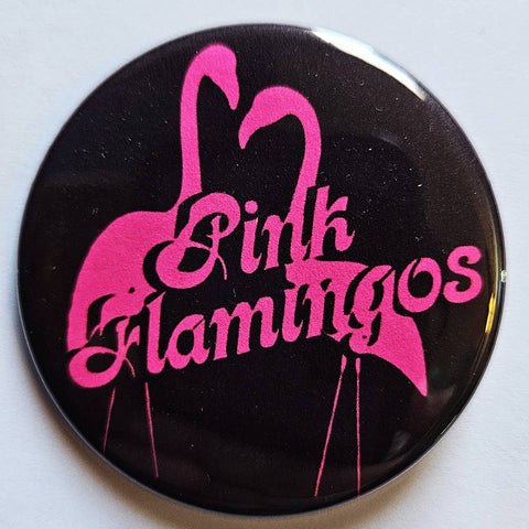 1.25" round pinback button with black background and neon pink pair of flamingos with "Pink Flamingos" written in matching script font