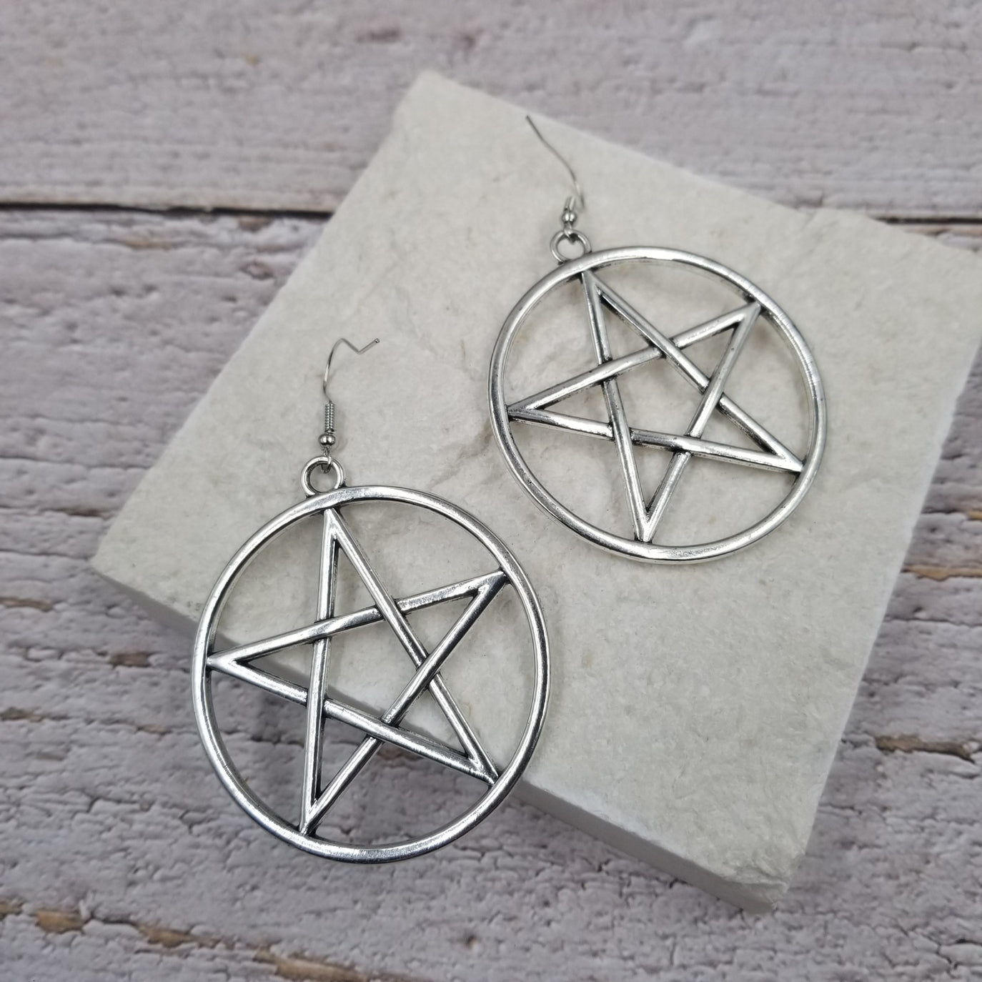 A pair of bold shiny silver metal 2" pentacle dangle earrings with matching metal fishhook style ear wires