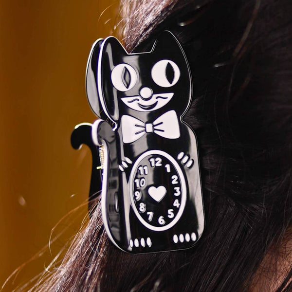 claw style hair clip in the shape of a black Kit-Cat Klock with white details including heart in middle of clock face on its stomach. Shown in updo hairstyle