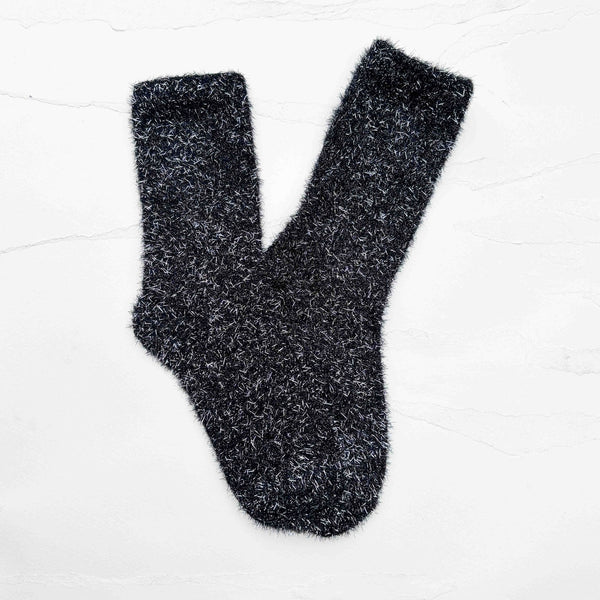 a pair of fuzzy knit crew length socks in black with long strands of silver lurex woven in and sticking out. Shown flat on white background