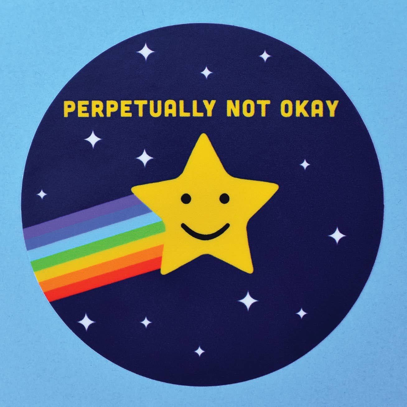 A round navy blue sticker with a yellow shooting star with a rainbow trail is in the middle of the sticker surrounded by small white stars. At the top are the words “Perpetually not okay” in yellow