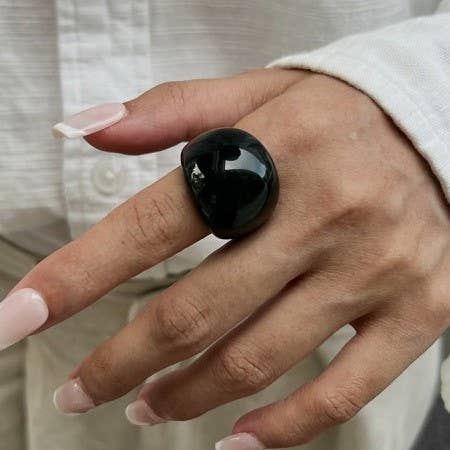 Hand wearing a wide rounded black ring made of shiny acrylic resin