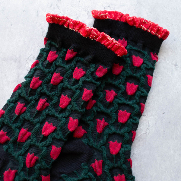 cotton knit socks in black with an allover red and green tulip knit-in pattern and a red and gold lurex ruffled cuff. Shown in close up