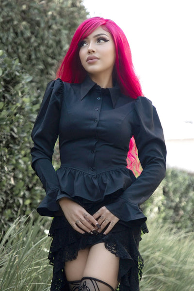 model wearing black chiffon long sleeve blouse with button-down front, pointed collar, exaggerated puffed shoulders, ruffled cuffs, and peplum style ruffled gathered bottom hem. Shown from front