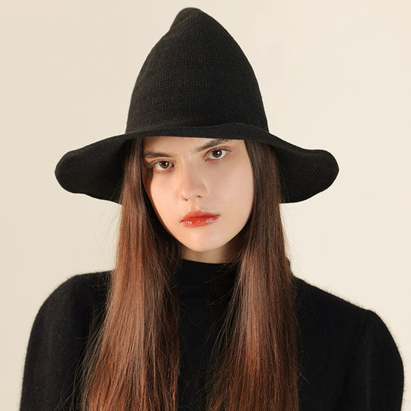 Woman wearing a black textured ribbed knit witch hat against a plain background. Shown from front
