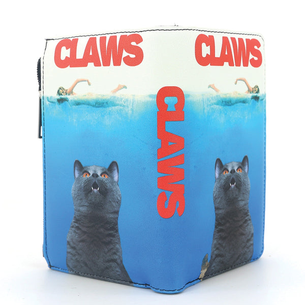 A zip-closure faux leather wallet featuring a graphic print of a gray cat in the water with the word 'CLAWS' in red at the top in the style of the JAWS movie poster, shown on a plain white background unzipped to display both printed sides